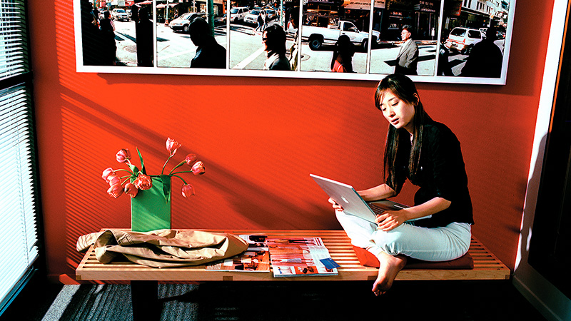 Young woman using laptop in oriental-style setting.